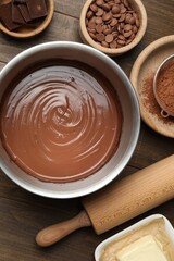 Chocolate dough in bowl and ingredients on wooden table, flat lay