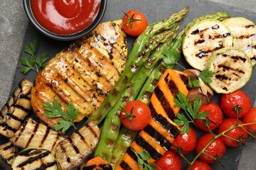 Delicious grilled vegetables and chicken breast served with sauce on grey table, top view