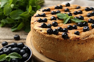 Delicious homemade blueberry pie with mint and fresh berries on wooden table, closeup