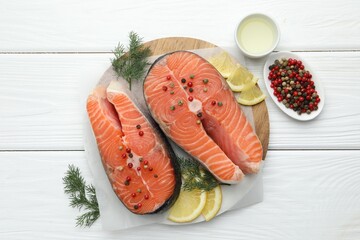 Fresh raw salmon steaks with peppercorns, lemon, oil and dill on white wooden table, flat lay