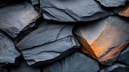 A close-up image featuring dark grey slate stones with rough textures, arranged in a natural formation, depicting strength, permanence, and natural beauty.