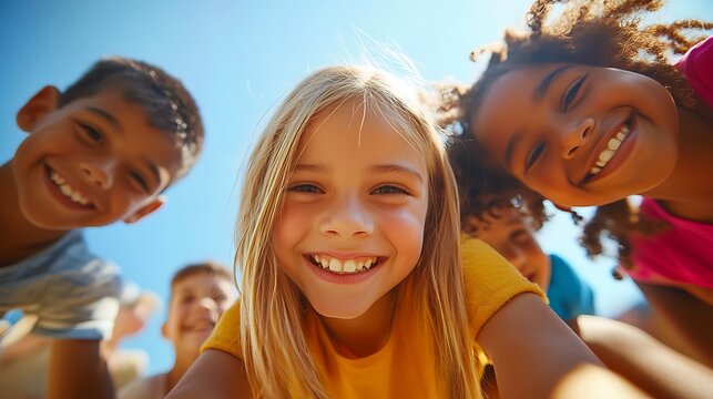 Multiethnic children with big smiles lean towards the camera from a low angle.