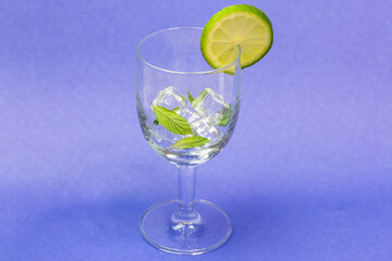 A glass of water with a lime slice and mint leaves floating on top