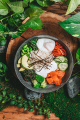 Vibrant sushi bowl filled with a variety of fresh vegetables, rice, salmon, beans and avocado elegantly presented on a wooden plate, surrounded by lush greenery, creating a refreshing ambiance.