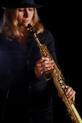 soprano saxophone in the hands of a girl on a black background