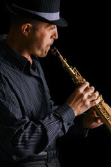 Naklejka premium soprano saxophone in the hands of a guy on a black background
