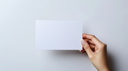 A hand holds a blank, white book or booklet.

