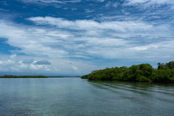 Beautiful island scenery with a bright blue sky, green foliage, and calm waters reflecting the natural beauty of the coastline, environment for travel, summer vacations, peaceful retreats