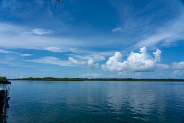 Beautiful island scenery with a bright blue sky, green foliage, and calm waters reflecting the natural beauty of the coastline, environment for travel, summer vacations, peaceful retreats