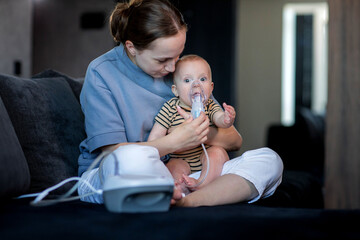 Woman with infant son makes inhalations using a nebulizer at home