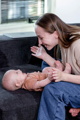 Mother is playing with her little son on the couch at home. Motherhood