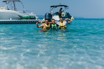 Group of friends enjoying speedboat tubing in clear blue sea on a sunny summer day