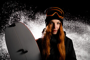 Young pretty smiling female snowboarder holding her splitboard next to her