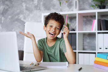 Portrait of cheerful smiling carefree schoolboy happy to have online lesson, e-learning, distant...