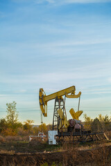 Oil well drilling rig in the middle of autumn field on a clear evening