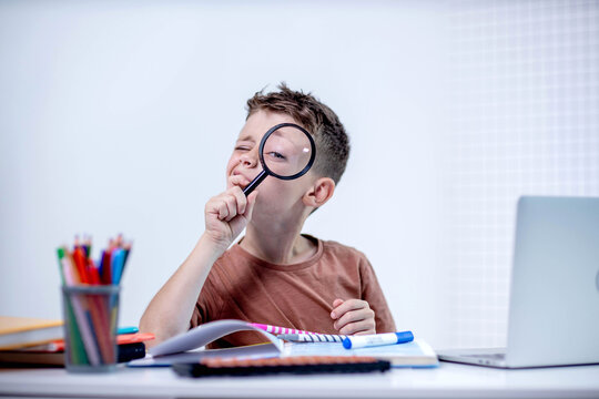 School boy looking at camera through a glass loupe. Education, knowledge, discoveries concept