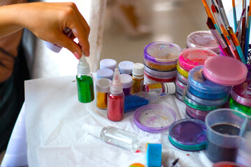 hand takes Glitter in plastic bottles. Decorative sequins to give shine, create festive atmosphere. make-up tools for face painting master. painting with glitter. various bottles. High quality photo