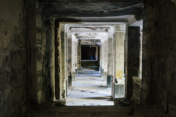 Obraz premium Dark, decaying hallway in abandoned building, crumbling walls and debris scattered on floor. 