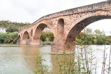 a stone bridge spanning over a river in the countryside .Puente La Reina, Navarra, Spain