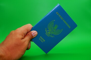 hand holding indonesian passport isolated on green background