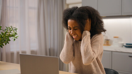 Annoyed angry woman African American businesswoman freelancer online working laptop at home kitchen...