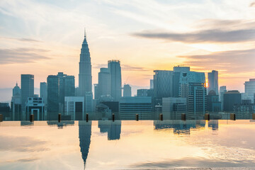 Kuala Lumpur city aerial view with reflections of high-rise buildings and skyscrapers in infinity roof top pool at sunrise, Malaysia. Downtown financial and business center of Asian city