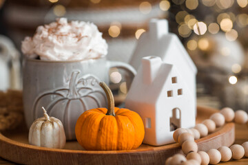 Delicious pumpkin latte with whipped cream and cinnamon in a mug on the table in the living room interior. Autumn decor in the house. Scandinavian style.