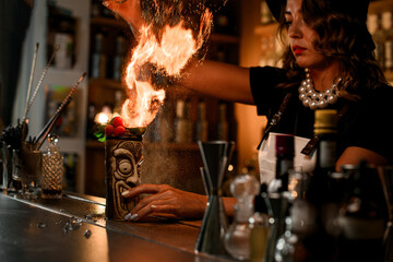 On the bar stands a shaped glass with a cocktail, decorated with mint leaves and raspberry berries