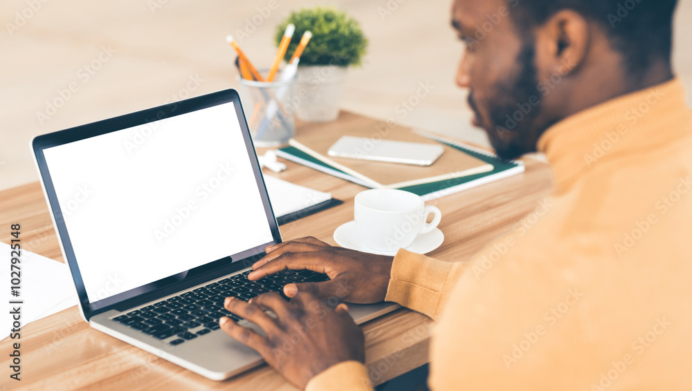 Poster mock up template. rear view of black man working on laptop with blank screen, typing on keyboard, co