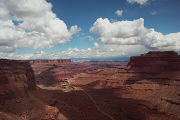 Desert Mesas Descending into a Valley Under a Blue Sky with Puffy Clouds