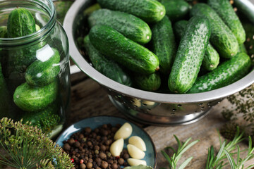 Fresh cucumbers, herbs and spices on wooden table, closeup. Preparation for pickling