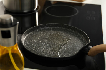 Frying pan with oil on cooktop in kitchen, closeup