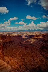 Vast Desert Mesas Leading to a Valley Under a Clear Blue Sky Adorned with Puffy Clouds