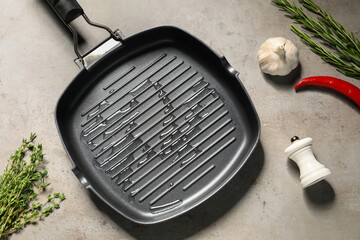 Frying pan with oil and spices on gray textured table, flat lay