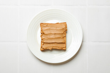 Delicious sandwich with peanut butter on white tiled table, top view