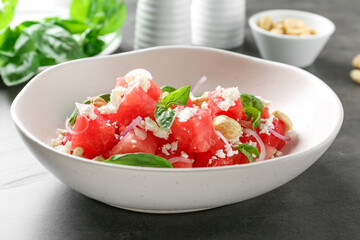 Tasty salad with watermelon, feta cheese and basil on black table