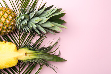 Fresh ripe pineapples and palm leaves on pink background, flat lay. Space for text