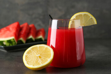 Delicious watermelon drink in glass and fresh fruits on dark grey table, closeup