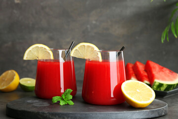 Delicious watermelon drink in glasses, fresh fruits and mint on grey table