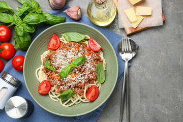 Delicious pasta bolognese with basil and tomatoes served on grey table, flat lay