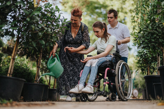 An elderly woman, a girl in a wheelchair, and a boy with Down syndrome enjoy gardening together. They illustrate community, inclusivity, and the joy of shared activities in a lush garden setting.