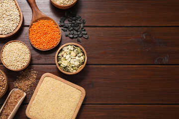 Different types of cereals, seeds and legumes on wooden table, flat lay. Space for text