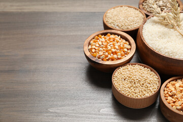 Different types of cereals in bowls on wooden table, closeup. Space for text