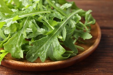 Fresh green arugula leaves on wooden table, closeup