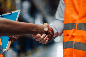 Two business partners shaking hands in warehouse