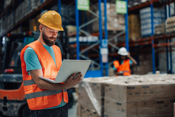 Warehouse worker using laptop checking inventory in logistics center