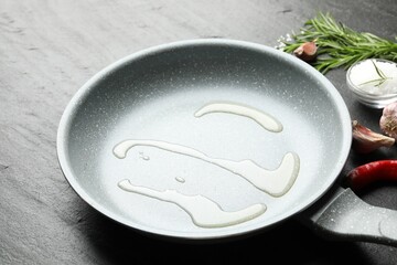 Frying pan with cooking oil on dark textured table, closeup