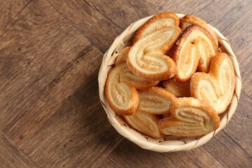Tasty french palmier cookies in wicker bowl on wooden table, top view. Space for text