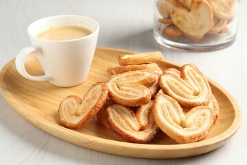 Delicious palmier cookies with coffee on white wooden table, closeup