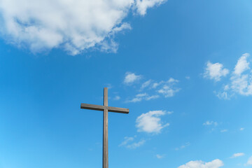 An Orthodox wooden cross on a background of blue sky and clouds. An old antique cross close-up.